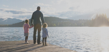 Father with two young children looking out into a lake